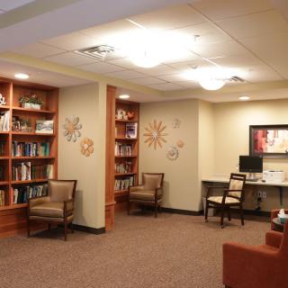 A cozy library space with bookshelves, comfortable chairs, and a computer desk.
