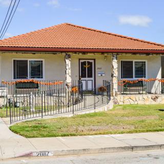 A single-story suburban house with a tiled roof and a fenced front yard.