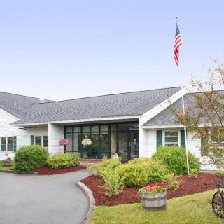 A well-maintained building entrance with lush landscaping and an American flag.