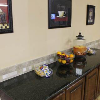 A decorated kitchen countertop with a fruit bowl and glass container, accompanied by framed artwork on the wall.