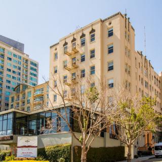A view of a multi-story apartment building in an urban setting on a sunny day.