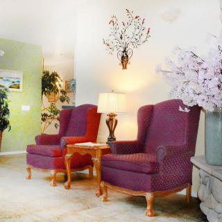 A cozy living room setup with two red chairs, a lamp, and floral decor.