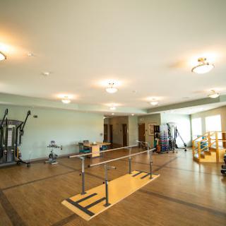 A spacious physical therapy gym equipped with exercise bars and various fitness equipment.