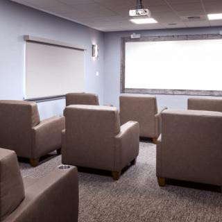 A home theater room with comfortable seating and a large projector screen.