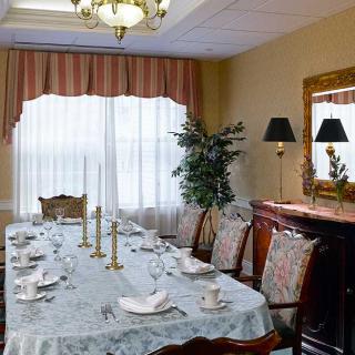 An elegantly set dining room featuring a long table with candlesticks, surrounded by ornate chairs and illuminated by a chandelier.
