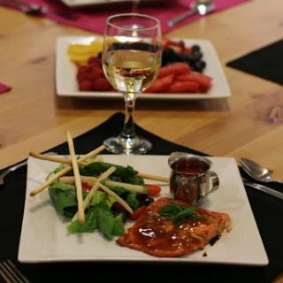 A beautifully plated salmon dinner with a side of fresh salad and a glass of white wine.