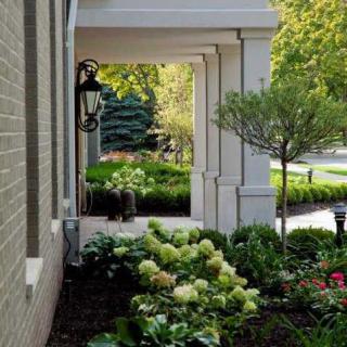 A beautifully landscaped garden with a pathway lined by flowers and shrubs adjacent to a building.