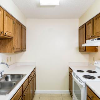 A compact kitchen with wooden cabinets and essential appliances.