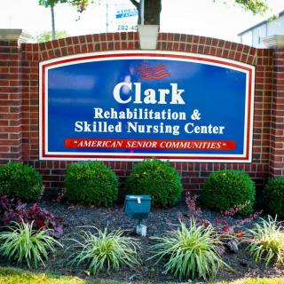 Sign for Clark Rehabilitation & Skilled Nursing Center surrounded by landscaped gardens.