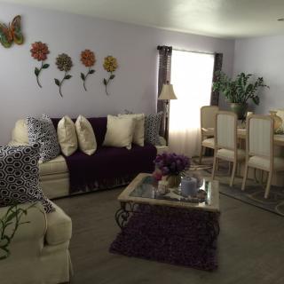 A cozy living room with a sofa, coffee table, dining area, and decorative wall art.
