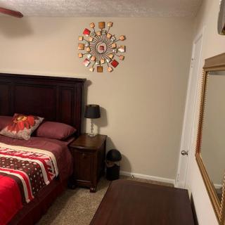 A cozy bedroom with a decorated wall, featuring a bed and a nightstand with a lamp.
