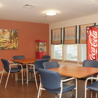 A cozy dining area with tables, chairs, a vending machine, and artwork on the wall.