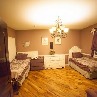 A cozy bedroom with twin beds, a chandelier, and wooden flooring.
