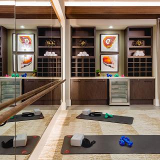 A well-equipped yoga room with mats, blocks, and resistance bands in front of mirrored walls and artwork.