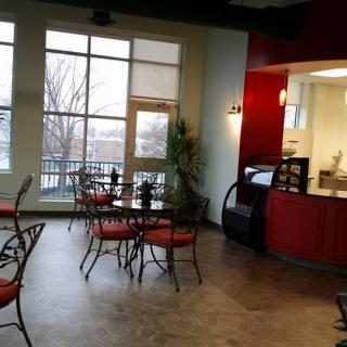 A modern cafe interior with empty tables and chairs, featuring large windows and red accents.