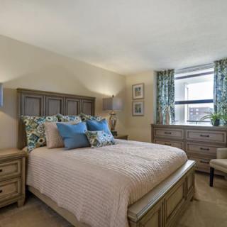 A cozy bedroom with a wooden bed frame, colorful pillows, and matching furniture.