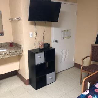 A simple setup in a hotel room featuring a television, storage unit, and a seating area.