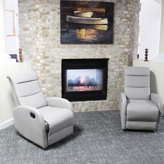 A cozy living room setup featuring two modern armchairs in front of a stone fireplace, complemented by a decorative painting above.