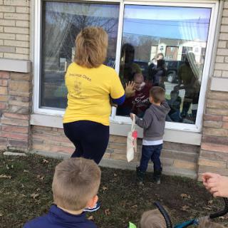 A heartwarming moment as children engage with an adult through a window during a community event.