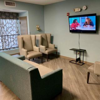 A cozy living room with a television, comfortable seating including a sofa and chairs.