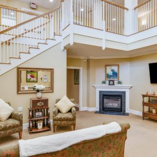 A cozy living room with a fireplace, elegant staircase, and comfortable seating.