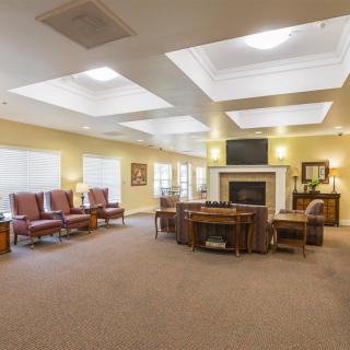A spacious and well-lit living area featuring multiple seating arrangements and a central fireplace.