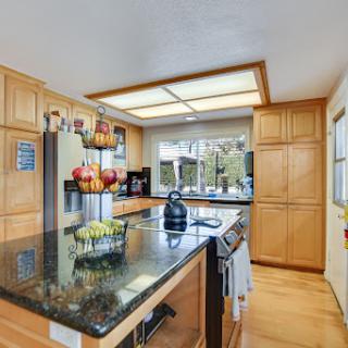 A modern kitchen featuring wooden cabinets, a black granite countertop, and ample natural light.
