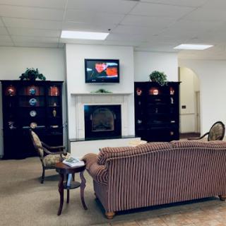 A cozy living room featuring a striped sofa, bookshelves, and a television above the fireplace.