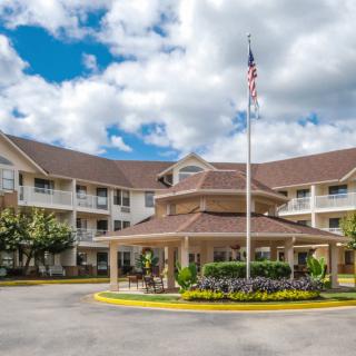 A residential building with a circular driveway and an American flag flying in front.