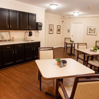 A neatly arranged dining area with tables, chairs, and cabinets in a well-lit indoor space.