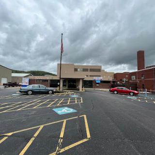 A view of a building with a parking lot under a cloudy sky.