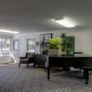 A well-furnished lobby area featuring a grand piano, comfortable seating, and decorative plants.
