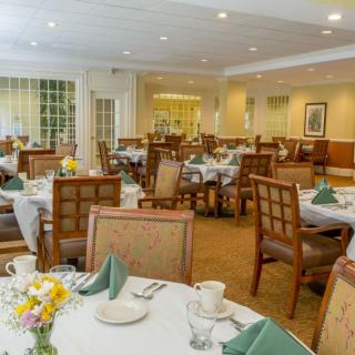A formal dining room set up with tables and chairs, featuring neatly arranged table settings.