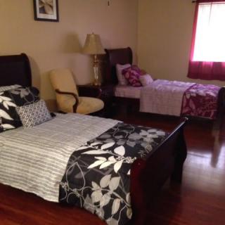 A cozy bedroom with a double bed and a single bed, featuring wooden flooring and warm lighting.