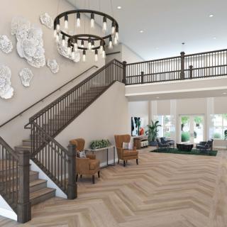 A modern lobby with a grand staircase, elegant chandelier, and comfortable seating area.
