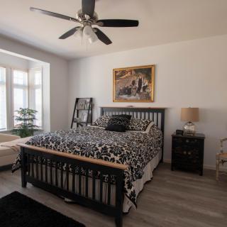 A cozy bedroom with a stylish black bed, decorative bedding, and a ceiling fan.