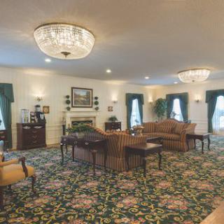 A traditionally decorated living room with chandeliers and floral carpet.