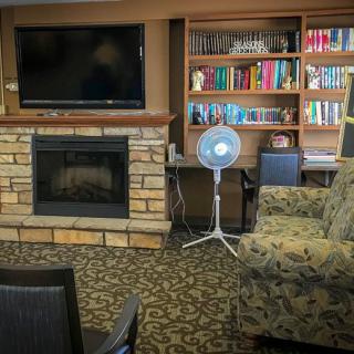 A cozy living room featuring a stone fireplace, a large television, and a bookshelf filled with books.