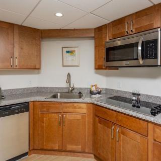 A modern kitchen with wooden cabinets, a sink, and built-in appliances including a microwave.