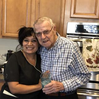 Two people smiling and hugging in a kitchen.