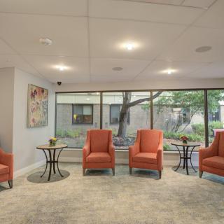 A modern waiting room with orange chairs and large windows.