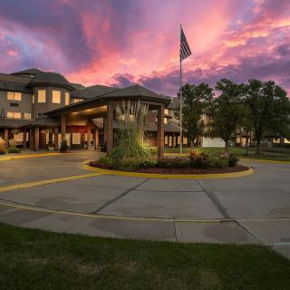 A beautiful sunset over a building with an American flag in the foreground.