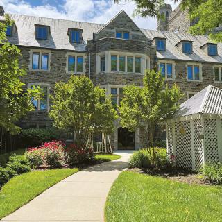 A charming building with stone architecture and a landscaped garden.