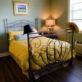 A cozy bedroom with yellow bedding and hats on the bedpost.