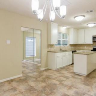 A modern kitchen and dining area with white cabinets, tile flooring, and contemporary lighting.