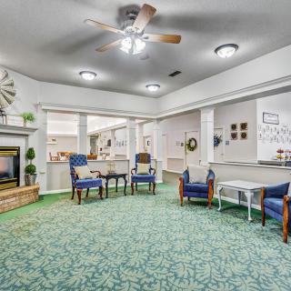 A cozy living room with comfortable chairs and a fireplace, featuring elegant interior decor and a green carpet.