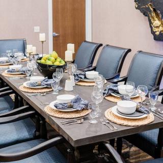A stylishly set dining table with blue chairs and a centerpiece fruit bowl, creating an elegant ambiance.