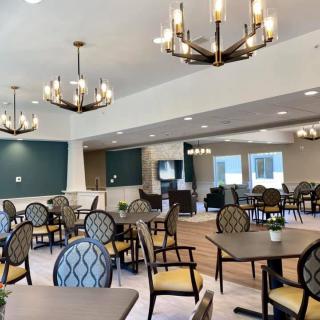 A spacious dining area with elegant chandeliers and neatly arranged tables and chairs.
