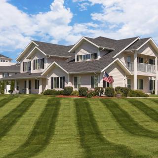 A large house with a beautifully manicured lawn and clear sky.