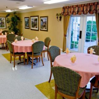 A well-arranged dining area with round tables covered in pink tablecloths, surrounded by chairs and decorated with art on the walls.